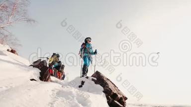 年轻的登山者<strong>全副武装</strong>，手里拿着滑雪杆站在山顶上，欣赏风景