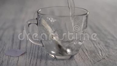 热水倒在一个杯子里，杯子里放着一袋凉茶，放在灰色的木桌上