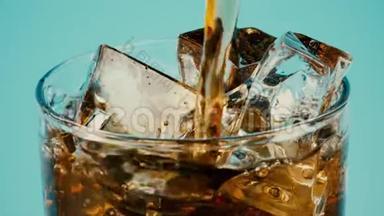 在青色背景下，将可乐或棕色软饮料倒入装满冰块的玻璃杯中，特写慢镜头继续拍摄