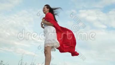 穿着红色斗篷站在球<strong>场上</strong>的女孩，扮演超级<strong>英雄</strong>。 开朗的女人穿着红色斗篷，表情开朗