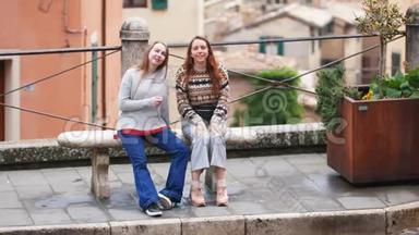 两个年轻的女人坐在长凳上。 <strong>四处</strong>走动的人
