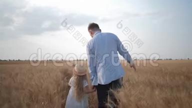 一家人在田里散步，年轻的父亲和小女儿一起散步，抚摸着阳光明媚的小麦穗。