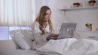 从清晨起，可爱的女孩就在笔记本电脑上工作，穿着浴袍，自由职业