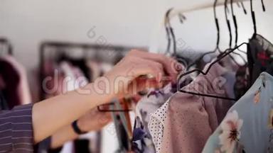 女人的贴身`在商店里的衣架上挑选衣服。 名牌服装、时尚服装、丝绸上衣