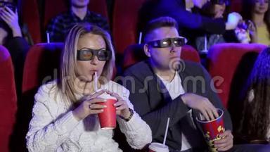 快乐的一对夫妻坐在电影院，看3D电影，吃爆米花，微笑