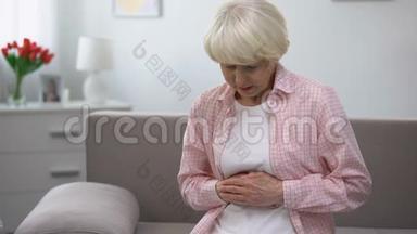 烦躁的老妇人用手握胃，患胃炎