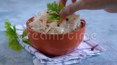 女人的手在碗里装饰欧芹泡菜。 健康、益生菌食品