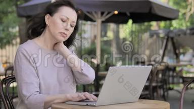 颈部疼痛的老女人使用笔记本电脑户外