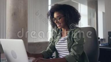 年轻女子坐在笔记本电脑前的办公桌前伸伸胳膊