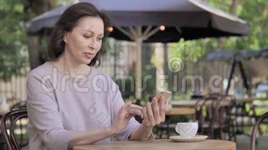 坐在户外咖啡厅的智能手机上的老女人追求成功