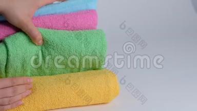 双手特写，把一叠新的浴巾放在床单上。 客房服务员清洁酒店客房