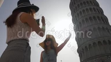 一个女人给她的朋友拍照，<strong>告诉</strong>她如何在照片上触摸倾斜塔。 意大利-比萨