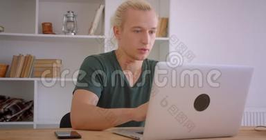 年轻英俊的金发时髦商人在笔记本电脑上浏览，并收到令人<strong>不</strong>安的<strong>通知</strong>