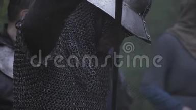 中世纪戴着金属头盔的战士正在雨中将他的剑鞘化