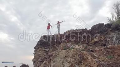 两个年轻快乐的女人在被大海包围的山上走来走去
