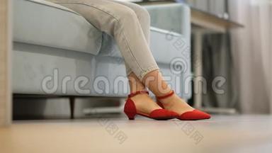 女人坐在沙发上，穿着漂亮的红鞋坐在木地板上