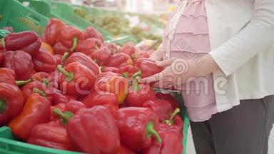 年轻孕妇在蔬菜店里选择红辣椒