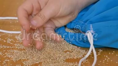 儿童手玩白色藜麦种子在蓝色可重复使用的包装在木制背景。 环保包装及健康