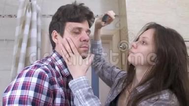 睡不着的夫妻在浴室里。 女人梳男人`头发，他们互相拥抱。
