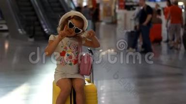 小女孩<strong>游客</strong>坐在<strong>火车站</strong>的一个大黄色手提箱上。 儿童正在等待出发，前往