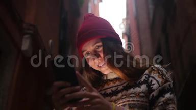 一个年轻微笑的女人站在街上，看着手机屏幕。 一道光照亮了她的脸
