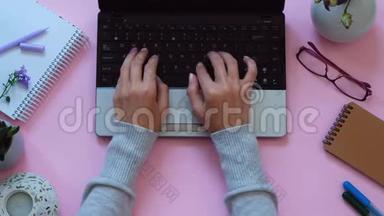女士`双手在笔记本电脑上工作，背景为现代粉色，工作空间，从上面看