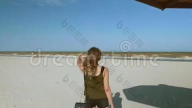 一个女孩站在荒芜的海滩上，手里拿着芦苇做成的<strong>沙滩伞</strong>。