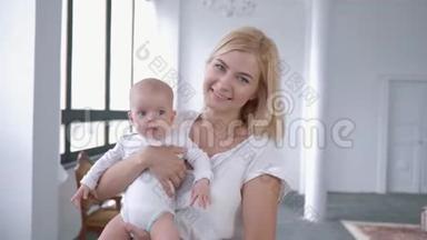 一幅家庭肖像，可爱的妈妈把刚出生的女儿抱在怀里，对着镜头微笑