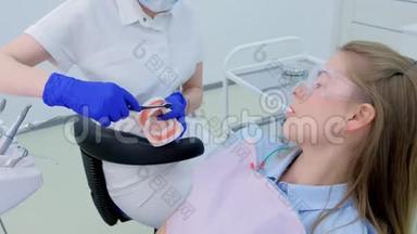 牙科医生向病人展示下颚模型如何<strong>正确使用</strong>牙刷清洁牙齿。