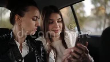 两个女朋友坐在<strong>汽车</strong>后座，分享手机<strong>屏幕</strong>显示内容。 朋友一起乘出租车