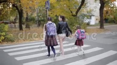 母亲带着女儿在秋天放学回家，在十字路口过马路。