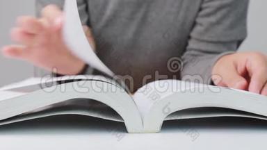 一个学生迅速翻开躺在白色桌子上的书页，合上文学封面。