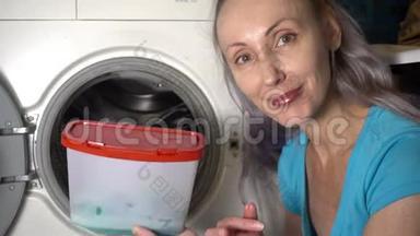 年轻女子准备在洗衣机里洗衣服，拿出并打开装有洗衣粉的盒子