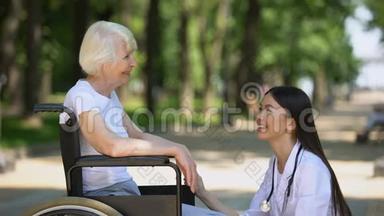 公园的微笑护士与残疾老年妇女交谈，康复中心