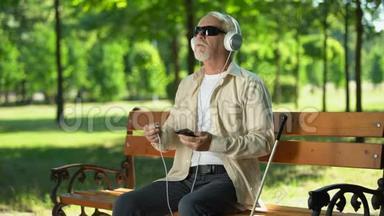 盲人老人把耳机电缆放在<strong>电话</strong>里，听<strong>语音</strong>信息，录音簿
