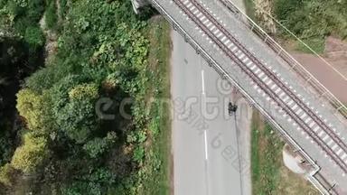 年轻女子骑自行车骑在铁路桥下。 铁路桥梁的俯视图.. 无人驾驶飞机从山路上飞过