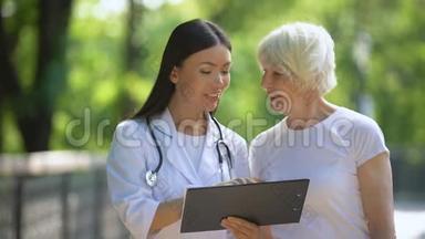 微笑护士显示医院公园内老年妇女检查结果
