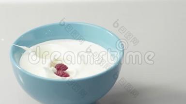 新鲜健康食品。 覆盆子掉进蓝碗里，配上酸奶和鲜奶油。 鲜果加鲜奶油。