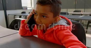 亚洲小学生在4k教室的课桌上用手机交谈的前景