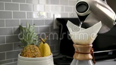 一个电热水壶的特写，把热水倒进一个滴水的咖啡瓶，背景是一个水果碗。
