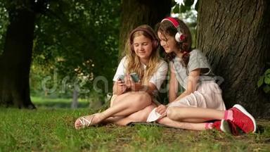 两个可爱的年轻姐妹带着耳机在美丽的日子里玩得开心。 快乐的孩子们在<strong>夏天</strong>公园玩。 看<strong>小孩</strong>