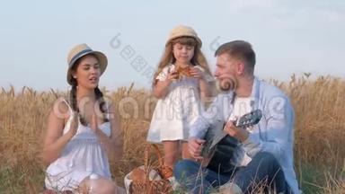 家庭乡村娱乐，年轻的爸爸在她那戴草帽和白裙的<strong>美女跳舞</strong>时弹吉他