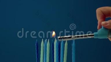 一些<strong>冷色调</strong>的蜡烛放在蓝色背景上，有人点蜡烛