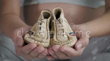 怀孕妇女展示她的双手漂亮的小鞋子，为婴儿贴身服务