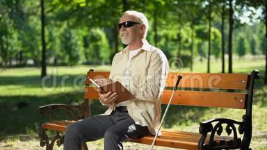 快乐的盲人养老金<strong>领取</strong>者在盲文书中阅读有趣的故事，享受公园的休息
