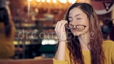 在一家舒适的咖啡店里戴着眼镜的迷人女孩的肖像
