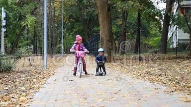 小男孩骑着滑板车，骑着<strong>平衡车</strong>，骑在柏油路旁，妈妈在城市公园附近散步。