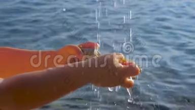 欧洲炎热的夏日。 孩子`他的手在水滴下，背景是海洋。 纯净水背景。 水