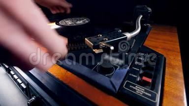 一个人把一个乙烯基盘放在一个音乐播放器上并启动它。