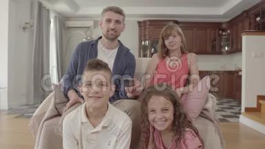 快乐的年轻家庭一起坐在家里看电视。 父亲拿着遥控器，打开频道